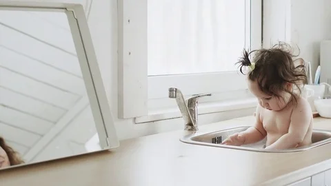 Baby taking bath in kitchen sink Stock Footage 79796956