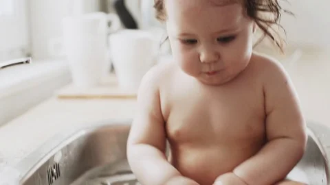 Baby taking bath in kitchen sink Stock Footage 79798396