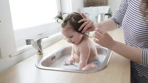 Baby taking bath in kitchen sink. Video stock 79923562