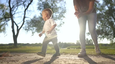 A baby is taking first steps in the grass. spring breastfeeding feet concept. a Video stock 316611332
