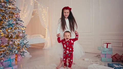 Baby taking first steps at home, holding hands with his sister in white dress. Stock Footage 166887154