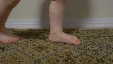 Baby taking first steps on rug seen in Slow Motion, Low angle shot Stock Footage 130855193