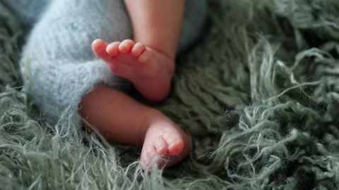 Baby tiny delicate bare feet and legs in blue knitted plaid Stock Footage 312953068