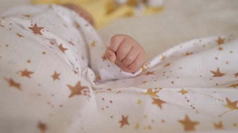 Baby tiny hand moving on cotton white napkin. Newborn kid is laying in the bed Stock Footage 166366652