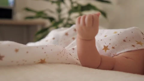 Baby tiny hand moving on cotton white napkin. Newborn kid is laying in the bed Video stock 166527451