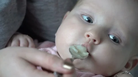 Baby trying vegetables for first time, mothers hand brings spoon to her mouth Stock Footage 70251804