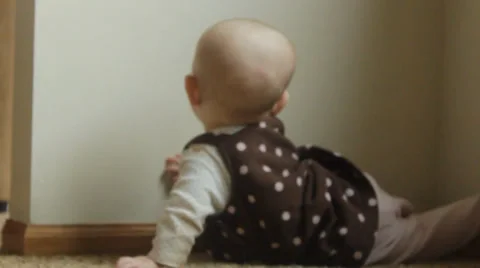 Baby turns back on camera while investigating the corner Stock Footage 35800780