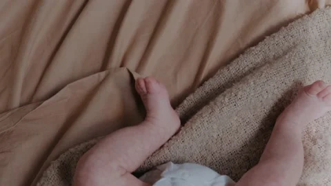 Baby twitches legs while lying on bed Stock Footage 194036156