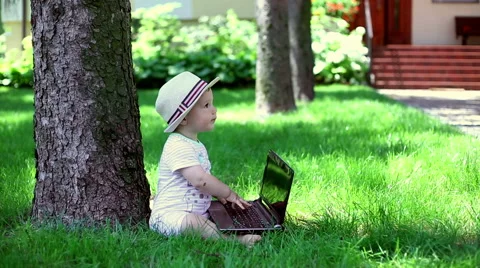 Baby using laptop in the garden  Video stock 64940237