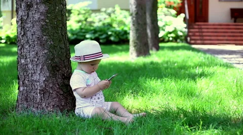 Baby using phone when it sitting in the garden  Video stock 64939192