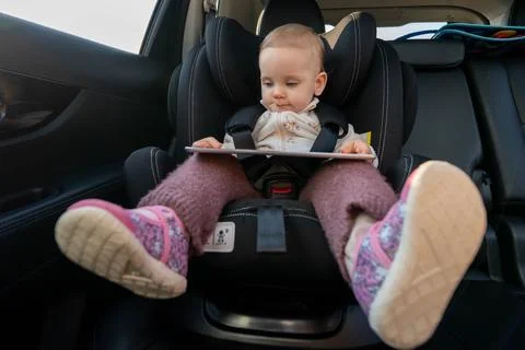 Baby using tablet while sitting in car seat. Concept of toddler digital Stock Photos