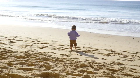 A baby walker discovers the sand and walks on the beach, in Portugal Stock Footage 213536376