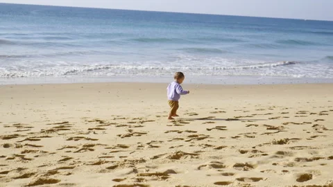 A baby walker discovers the sand and walks on the beach, in Portugal Stock Footage 213771127