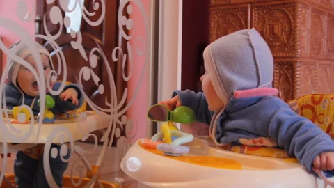 Baby in walker looking at reflection in the mirror Stock Footage 333301900
