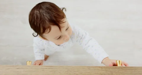 Baby, walking and fun exploring in the house playing with the cupboard knobs 動画素材 220851552