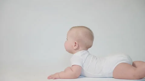 Baby on white background learn to roll over, first skills Stock Footage 237240461