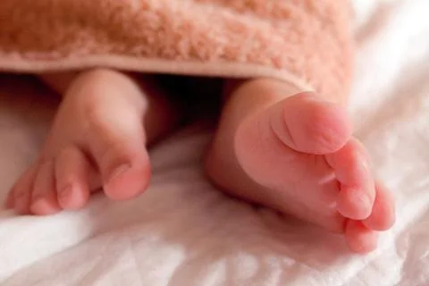 Baby on white blanket - tiny baby feet close up Stock Photos