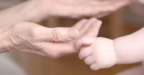 Babyhands touching senior hands Stock Footage