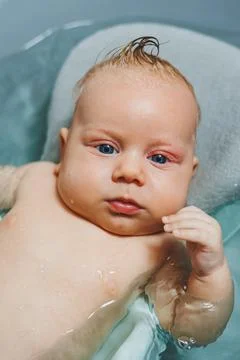 Baby's first baths. Caring for a newborn baby. Bathing a baby in a bathtub... Foto stock