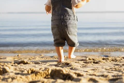 Baby's first steps on the beach towards the calm ocean water Stock Photos