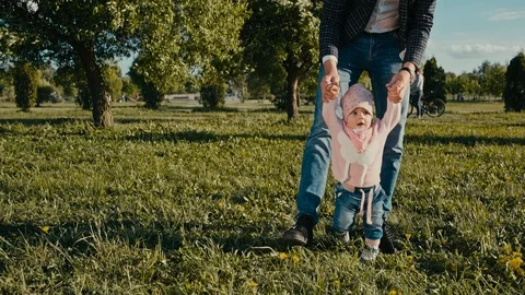 Baby's first steps. Dad helps to take the first steps his daughter Stock Footage 94440430