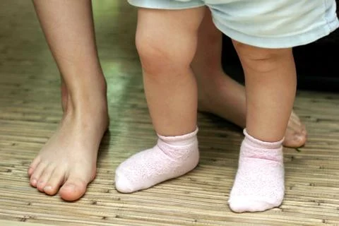 Baby's first steps. Small and large feet close-up. Teach your child to walk. Foto stock