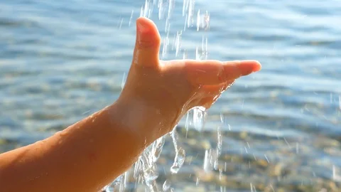 Baby's hand catching water drops on seascape background. Toddler's hand playing Stock Footage 113755317