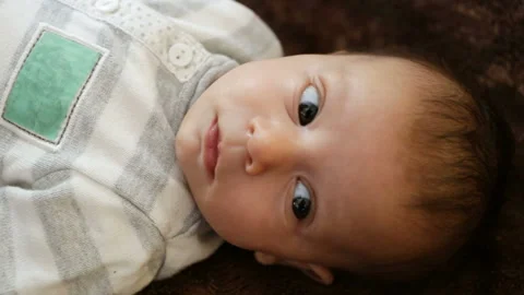 Baby's head close-up. The man touches the cheeks of the baby. The child looks to Stock Footage 86772809