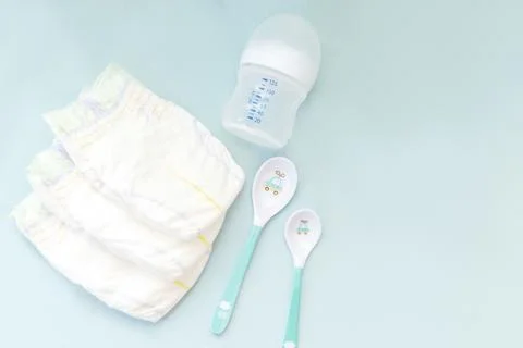 Baby's stuff with copy space. diapers with bottle for milk and spoons on bl.. Stock Photos