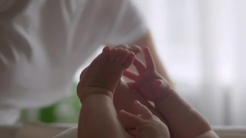 Babys tiny feet and hands close up, mom and baby playing at home, baby lies on a Stock Footage 303807258