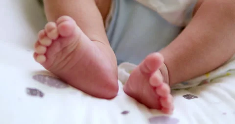 A baby's tiny feet are kicking and stretching as it is lying on its crib Vídeos de archivo 278570551