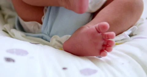 A baby's tiny feet are kicking and stretching as it is lying on its crib Vídeos de archivo 279628361