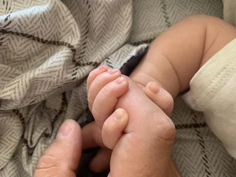 A baby's tiny hand gently gripping an adult's finger Foto stock