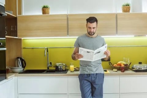 Bachelor man daily routine in the kitchen single lifestyle concept reading Stock Photos