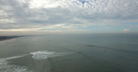 Back aerial flight of group of surfers in the distance Stock Footage 74222573