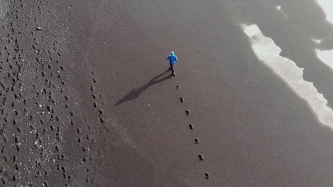 Back aerial view of young man running on the black volcanic beach in Iceland. Stock Footage 106450845