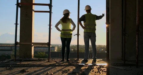 Back and side view of caucasian builder in White helmet and green vest looking Stock Footage 113047724