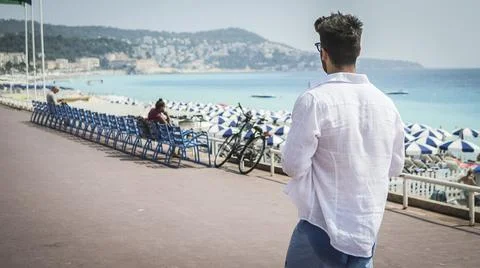 Back of athletic young man soaking in the sun on seaside boardwalk or seafront Stock Photos
