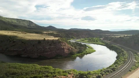 Back away from Colorado River by train tracks under red rock dry desert mesas Stock Footage 246433164