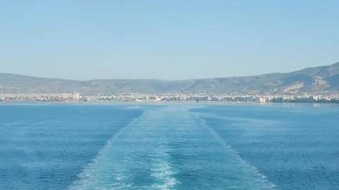 The back of a boat or ferry leaving Volos, showing the cityscape of Volos along Stock Footage 346678580