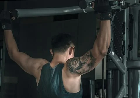 The back of bodybuilders exercise with lifting weights on an exercising mac.. Stock Photos