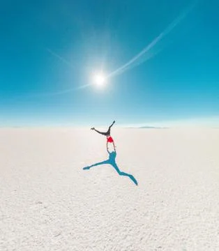 Back of a boy doing cart wheels at Uyuni salt flats in Bolivia. Sunflare Stock Photos