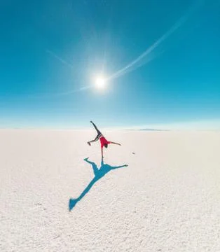 Back of a boy doing cart wheels at Uyuni salt flats in Bolivia. Sunflare Stock Photos