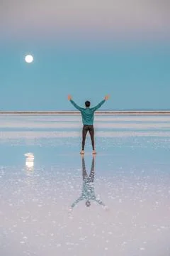 Back of a boy at Uyuni salt flats during sunset with the reflection of the moon Stock Photos