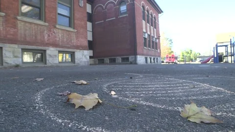 Back of brick school building, chalk on pavement, leaves, playground Stock Footage 304373227