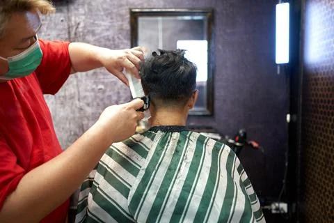 Back of a client sitting while having his hair cut in a barber shop Stock Photos