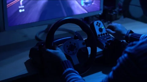 Back close-up shot of a man playing car racing video game using steering wheel Video stock 101872116