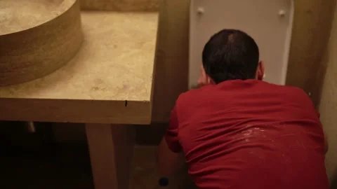 Back closeup view of man sitting on the floor of bathroom and vomiting then Stock Footage 167484476