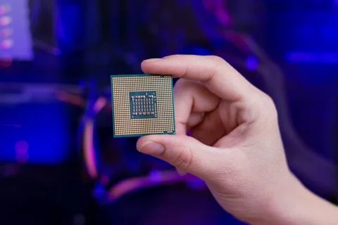 Back of a computer processor in hand. RGB light in background. Close-up. Stock Photos