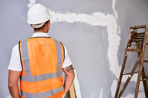 The back of a construction worker in uniform as he faces work in progress Stock Photos